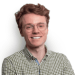 Smiling man with reddish-brown hair wearing glasses and a green and brown checked shirt.